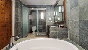 Un baño moderno con una bañera grande, ducha e inodoro.