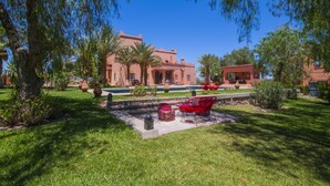 Un patio con piscina, palmeras y un edificio de techo rojo.