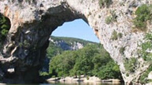 A natural rock arch over a calm body of water, surrounded by greenery and hills. - Charming studio 25 min from vallon pont d'arc (Le Garn)