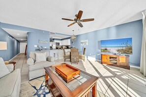 A modern living room with a sofa, coffee table, and a TV displaying a beach scene.