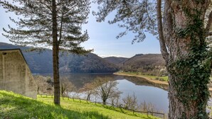A serene lakeside view with a concrete structure, a wooden fence, and lush greenery. - Vacancéole - Le Domaine de Confolant (Miremont)