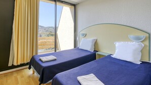 A hotel room with two beds, a large window with curtains, and a view of the countryside. - Vacancéole - Le Domaine de Confolant (Miremont)