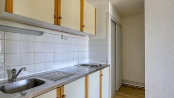 Een keuken met witte betegelde muren, houten kastjes en een roestvrijstalen spoelbak.