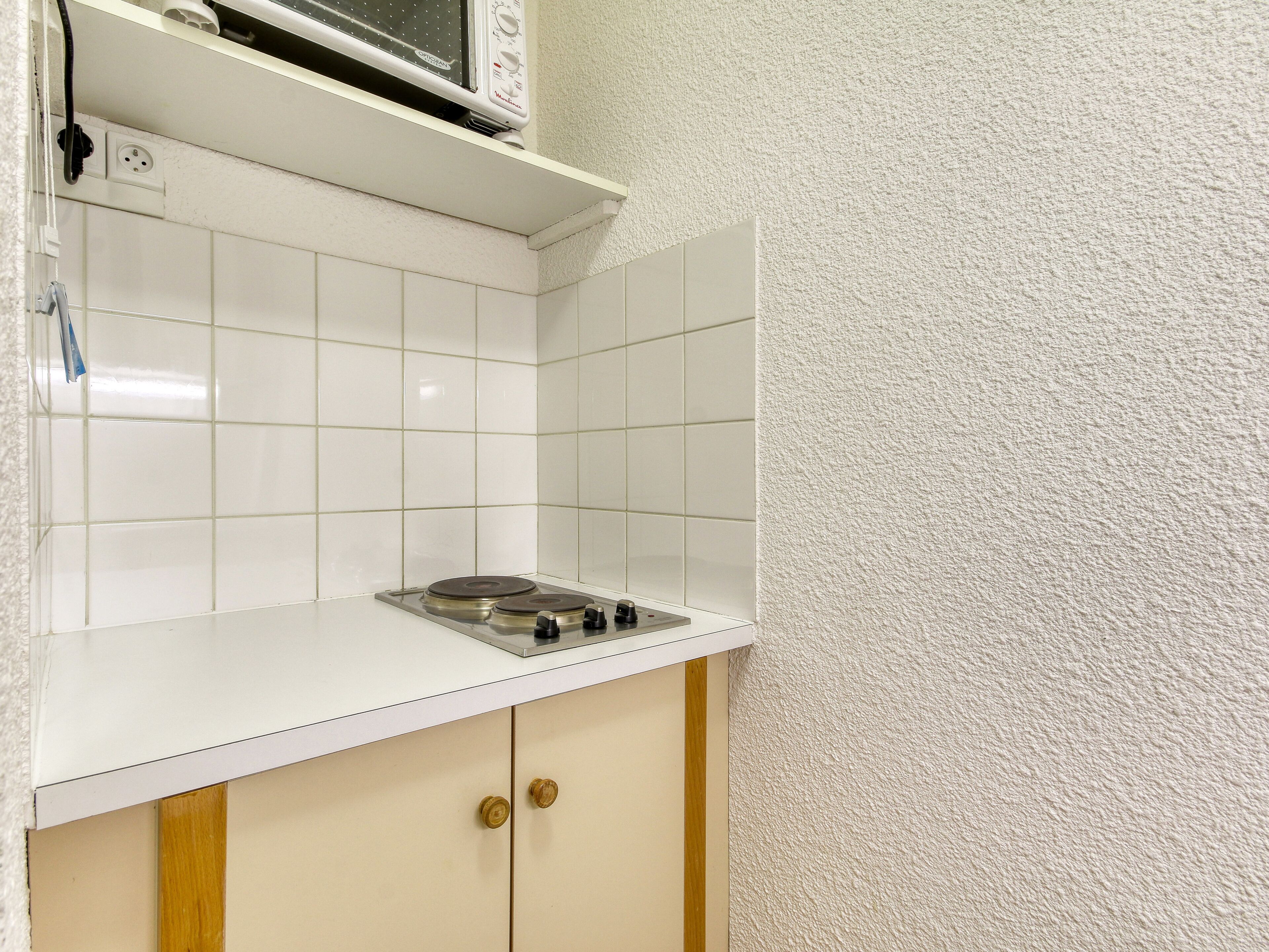 Una cocina con baldosas blancas, un microondas y una estufa.