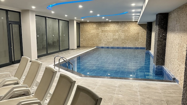 Ein Innenpool mit Liegestühlen und modernem Deckenbau.