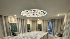 Ein geräumiger Raum mit einer großen, marmorplattenverkleideten Kücheninsel, Streifenwänden und einer dekorativen Glasdecke.