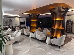 A modern lobby with a bar area, seating with tables, and a large bookshelf. - Side Golden Rock Hotel 16+ Adults Only (Manavgat)