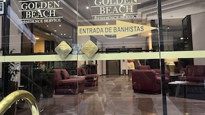 The entrance of Golden Beach Residence Service with a reception area visible inside. - Apartment with beautiful sea view - Praia de Pitangueiras (Guarujá)