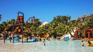 A water park with slides, pools, and palm trees.