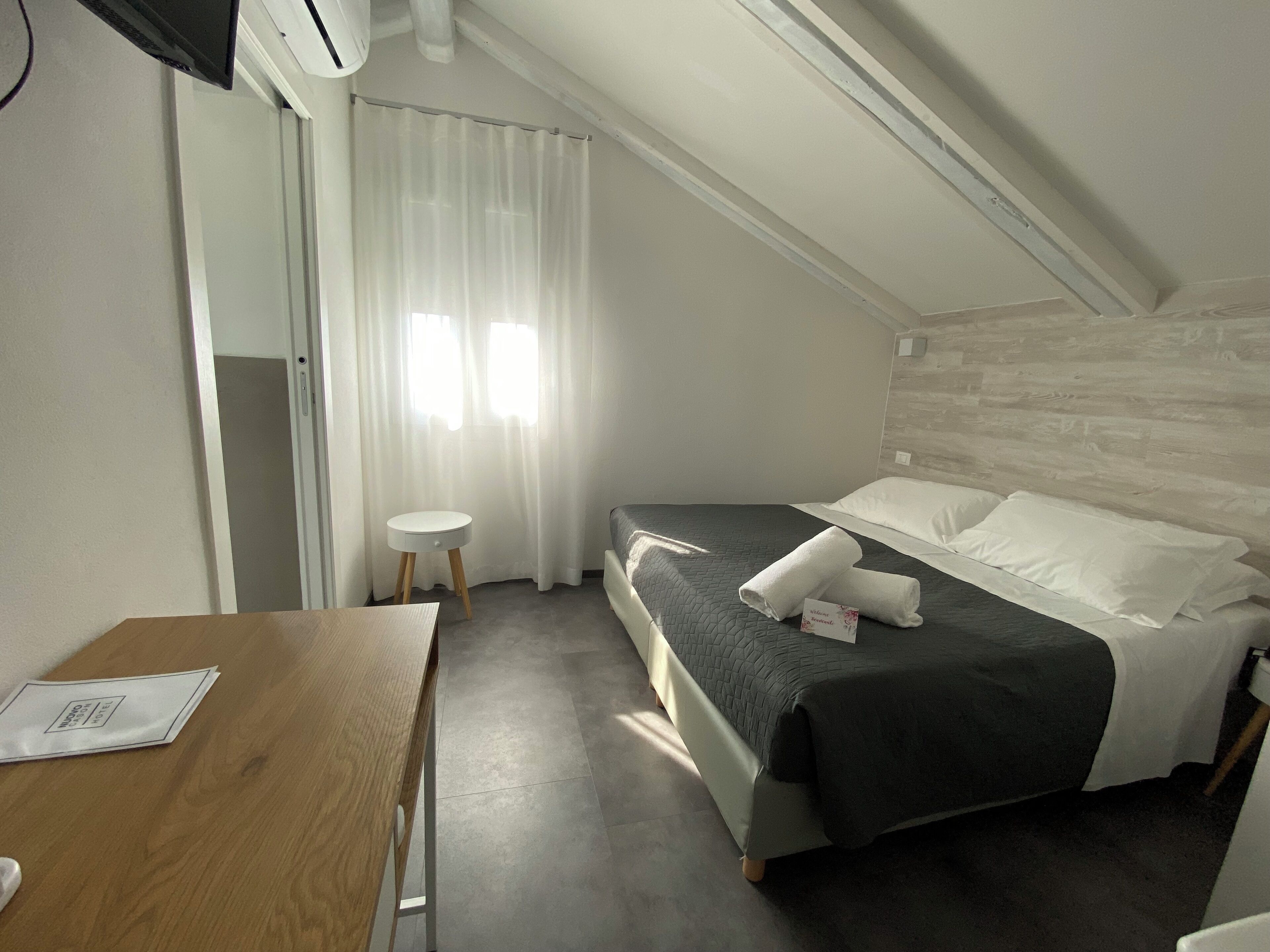 Habitación de hotel con cama, una mesita redonda, un escritorio y una ventana con cortinas.