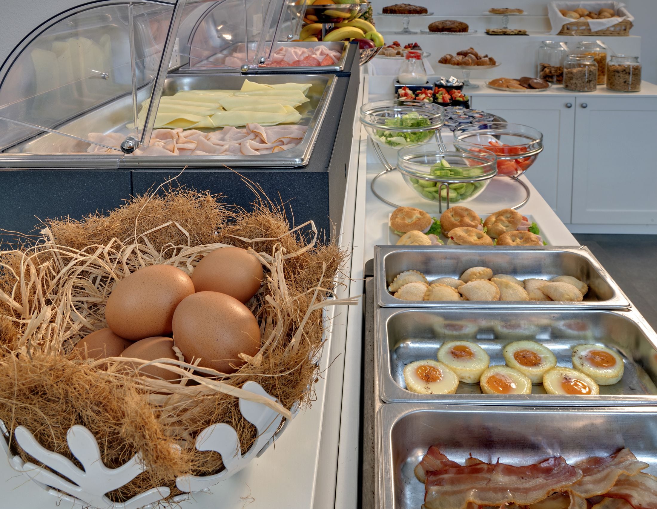 Un bufé con diversas opciones de comida, incluyendo huevos, tocino y pasteles.