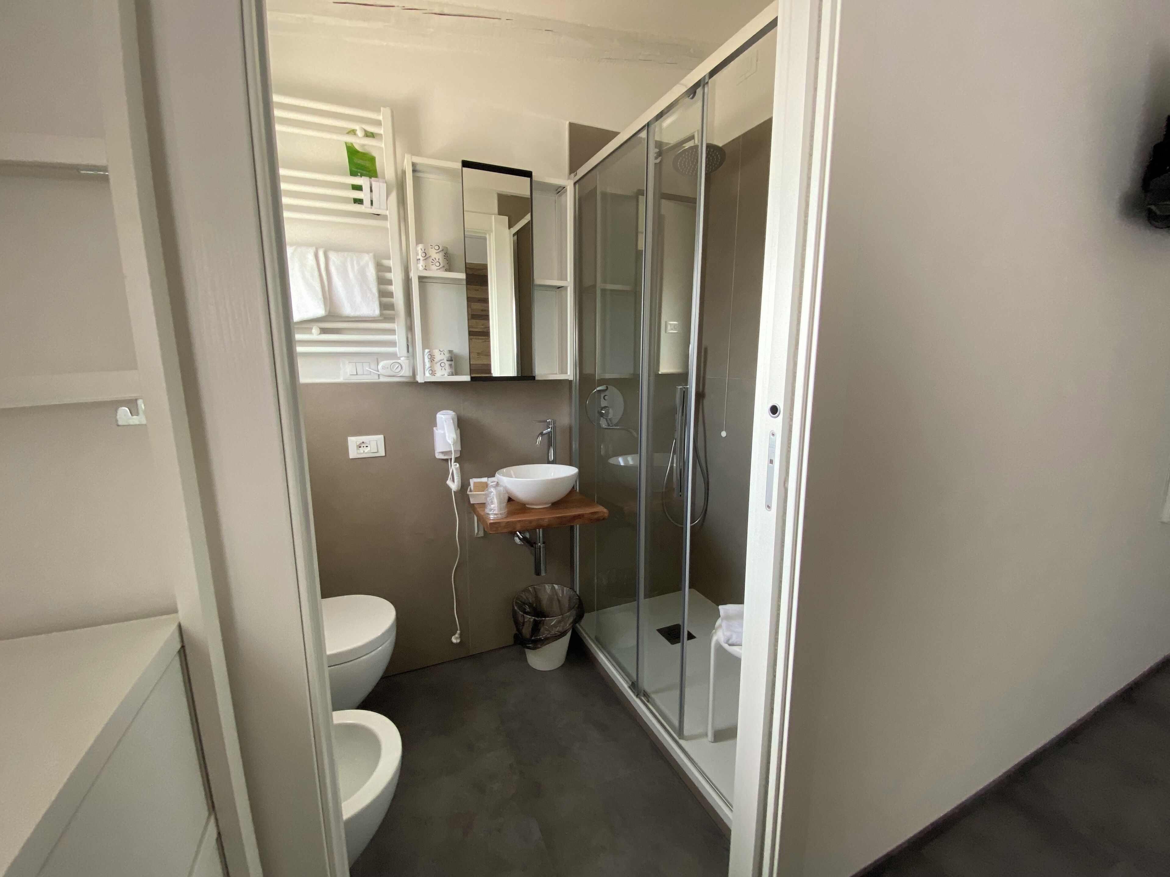 A modern bathroom with a glass-enclosed shower, a white sink, and a toilet.
