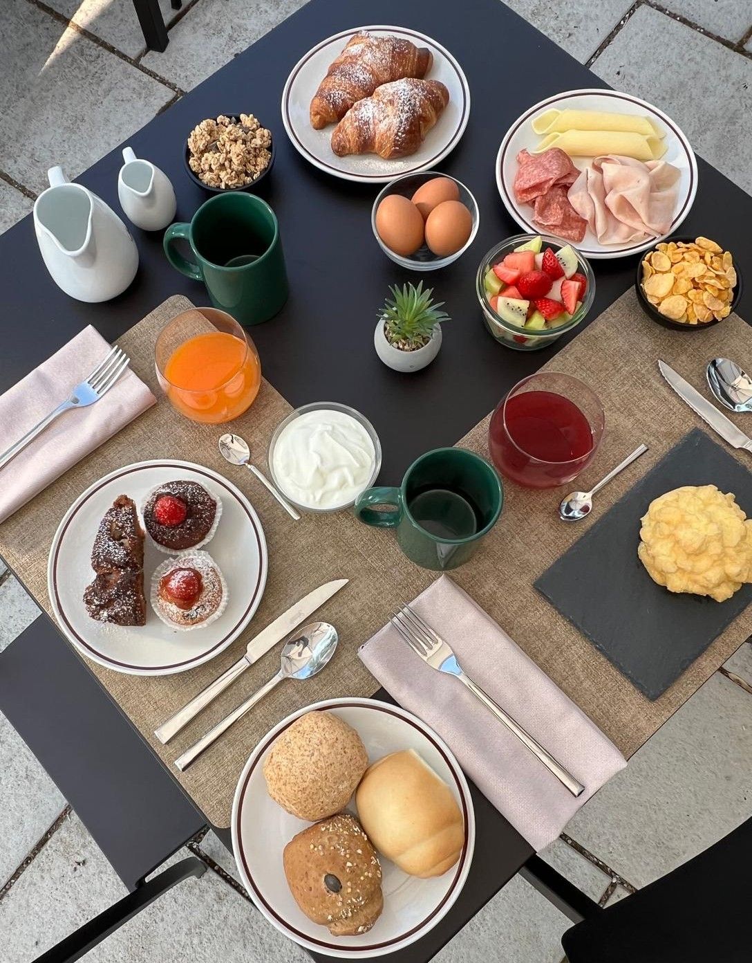 Une table dressée pour le petit-déjeuner, avec différents aliments et boissons.