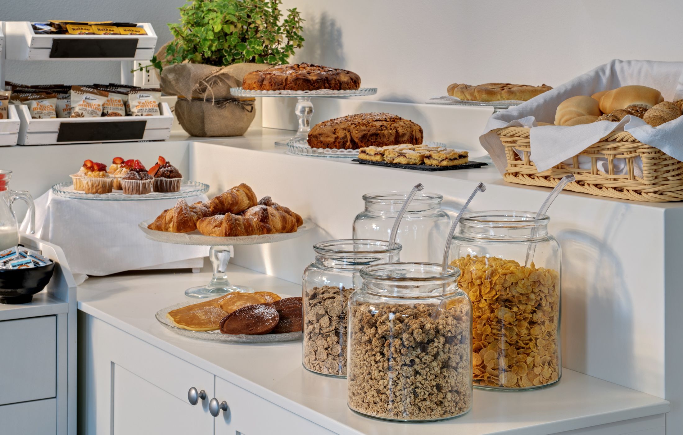 A buffet table with various baked goods, pastries, and cereal options.