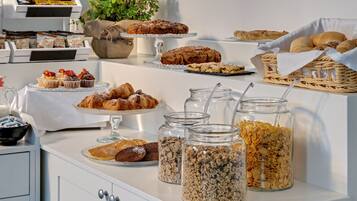 A buffet table with various baked goods, pastries, and cereal options.