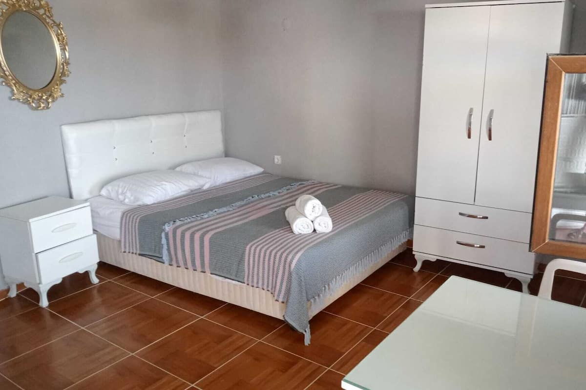 A bedroom with a bed, nightstand, wardrobe, and a table.