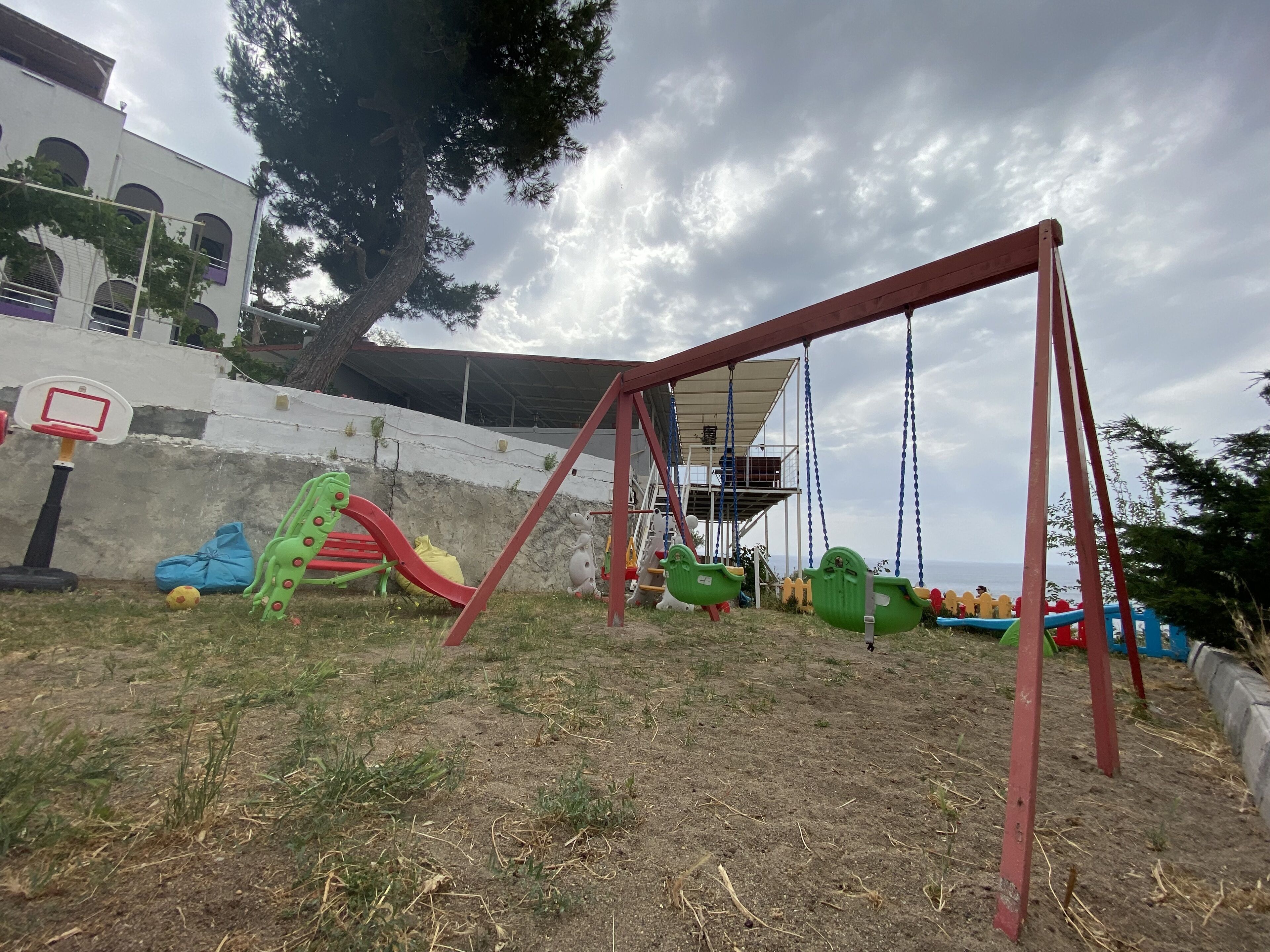 Un parque infantil con columpios, toboganes y un aro de baloncesto.