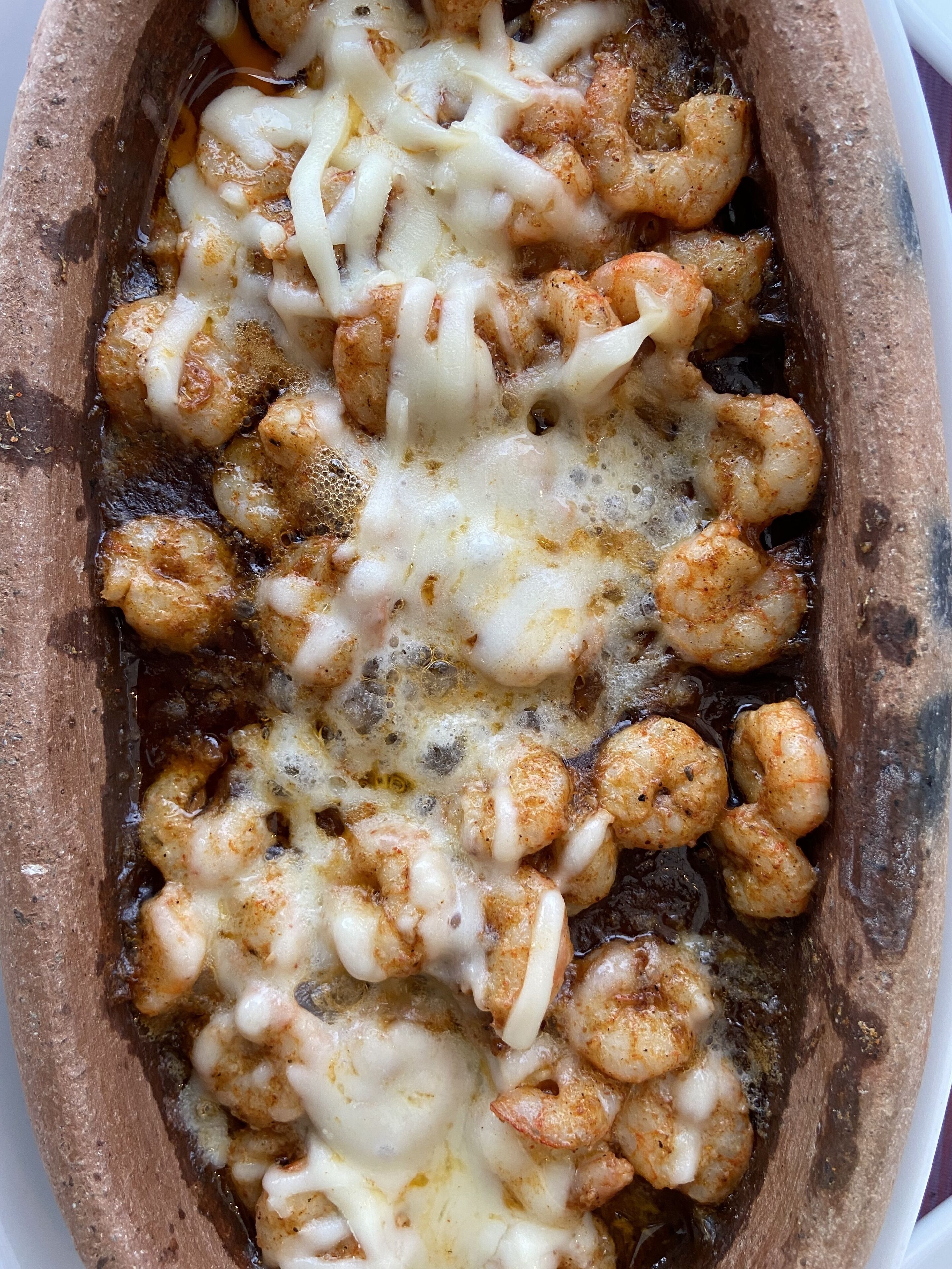 Un plato de camarones y queso fundido en un recipiente para hornear.
