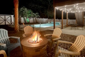 A backyard with a fire pit, outdoor seating, a pool, and a covered patio area. - Just Beachy | Beautiful Beach Home with Heated Pool (Surfside Beach)
