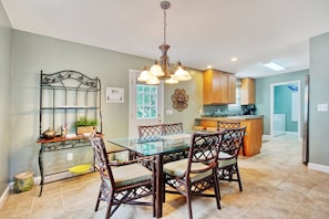 A dining area with a glass table, wicker chairs, and a chandelier.