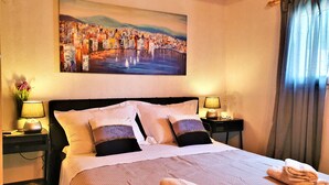 A hotel room with a bed, two bedside tables, a painting, and a window with curtains. - Holiday houses Escape A&B, 2x jacuzzi, sun terrace with a view, privacy (Drvenik Mali)