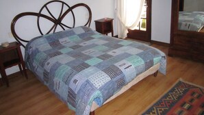 A bedroom with a wooden bed, a small bedside table, a bedside lamp, and a window with curtains. - Au Calme, Sans vis à vis (Saint-Jean-de-Luz)