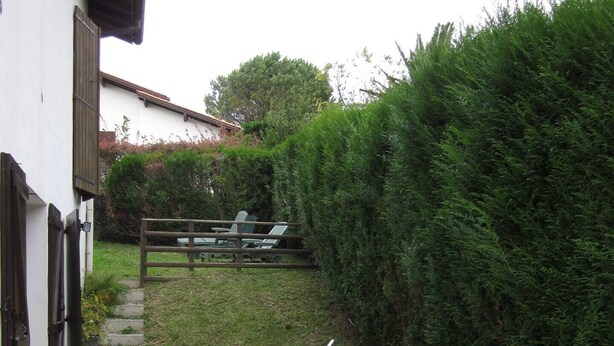 A patio with a stone pathway leading to a white table and chairs. - Au Calme, Sans vis à vis (Saint-Jean-de-Luz)
