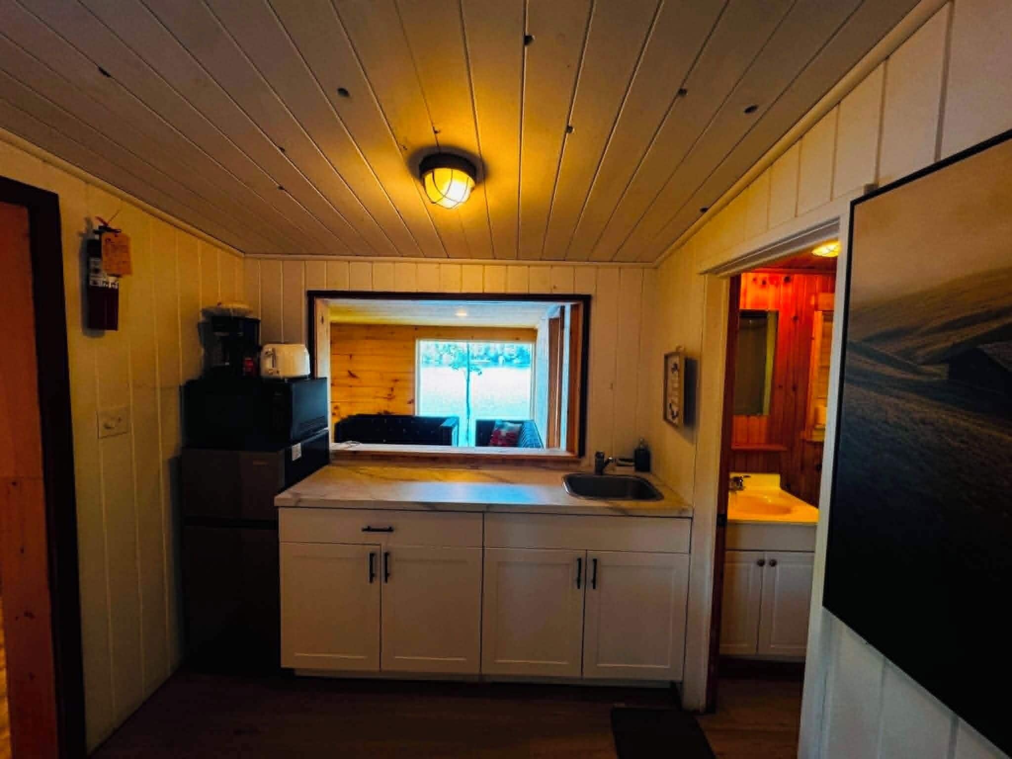 Une cuisine compacte avec des meubles en bois, un îlot central et une vue par la fenêtre.