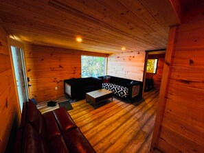 Interior de una cabaña de madera con un sofá, un televisor y un banco.