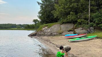 A sandy beach with kayaks and a bicycle.