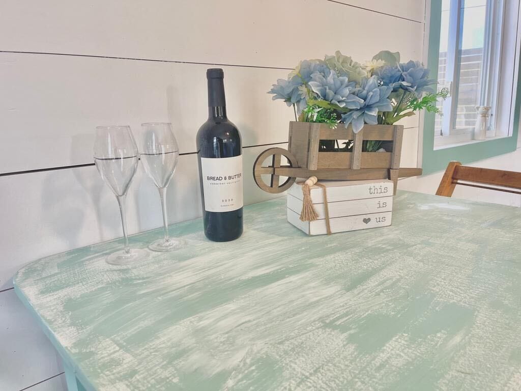 A table with a bottle of wine, two glasses, and a wooden box with flowers.