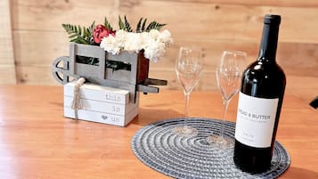 Una mesa de madera con una botella de vino, dos copas y una caja decorativa con flores.