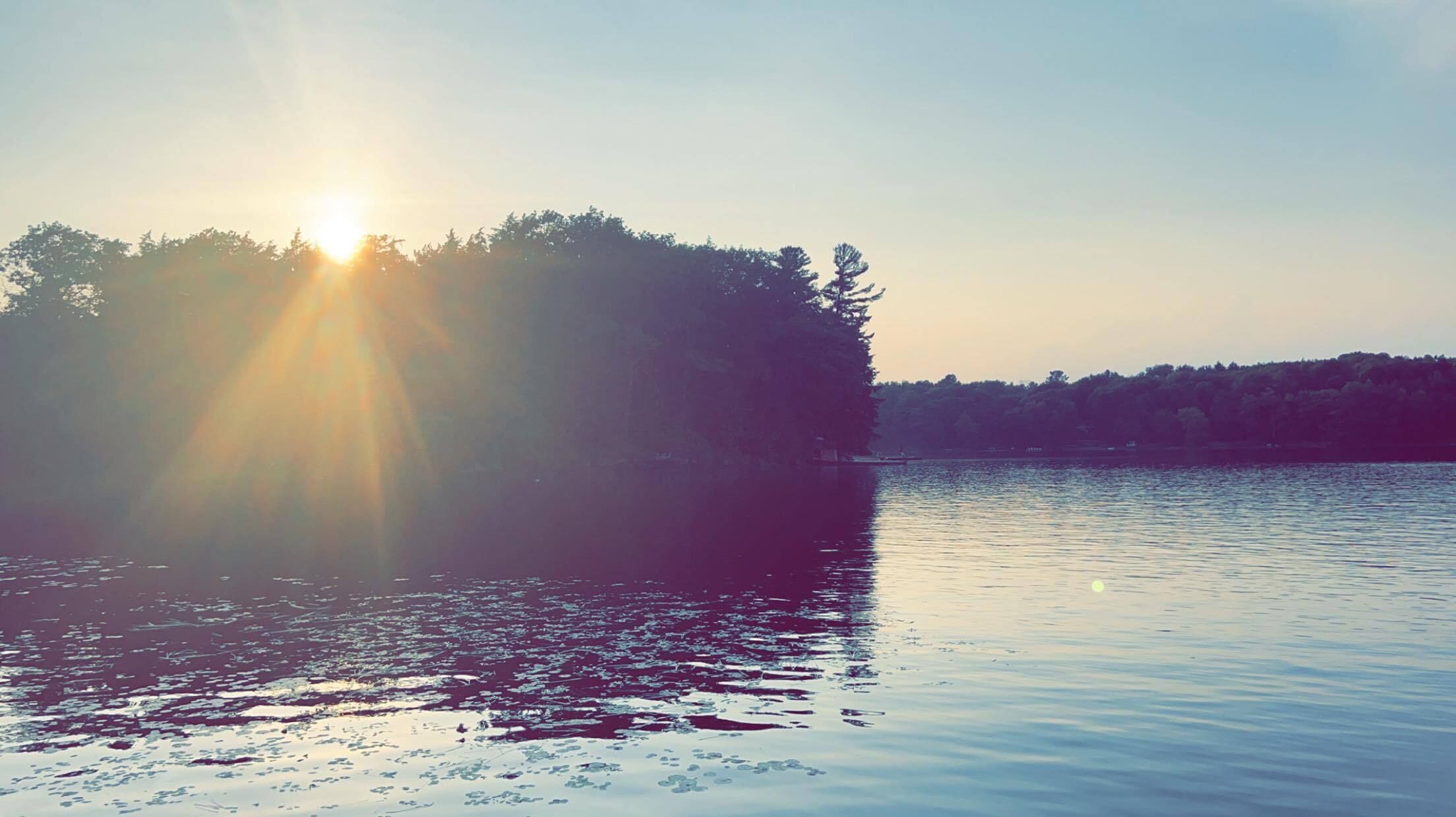 Ein ruhiger See mit einer sonnenbeschienenen Insel in der Mitte.