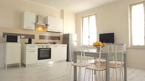Una cocina moderna con armarios blancos, horno empotrado y comedor con mesa y sillas.