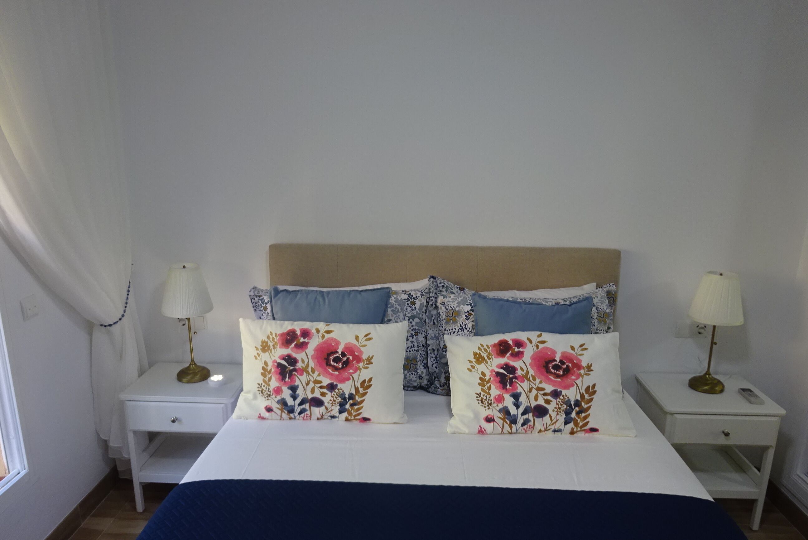 A bedroom with a bed, two bedside tables, and two lamps.