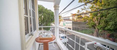 A balcony with white railings, a small round table, and white chairs.