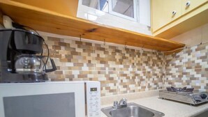 A kitchen with a microwave, a sink, and a gas stove. - Fully Equipped 1BR Studio ->DT->2Mins to the Beach (sosua)