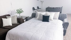 A neatly arranged bedroom with a large bed, a sofa, a small table with a plant, and a futsal table.