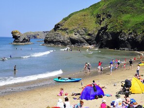 A beach with people engaging in various activities, including surfing and swimming.