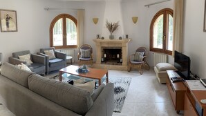 A living room with a sofa, armchairs, a fireplace, a television, and a dining area. - FAMILY VILLA WITH POOL NEAR MORAIRA (Teulada)