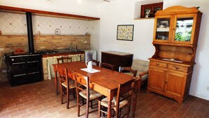 Una cocina con una mesa de madera, sillas, una estufa y un armario.