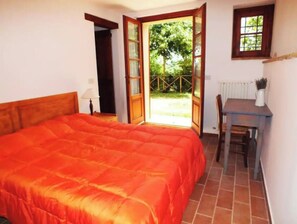 Relax in a spacious room with a large bed, wooden desk, and a window offering a view of the outdoors.