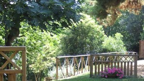 Un jardín con un pérgola de madera, plantas en macetas y un farol.