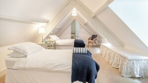 A bedroom with two beds, a chair, and a small table.