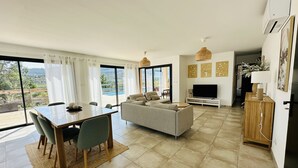 Una sala de estar moderna con un sofá, televisor y zona de comedor con mesa y sillas.