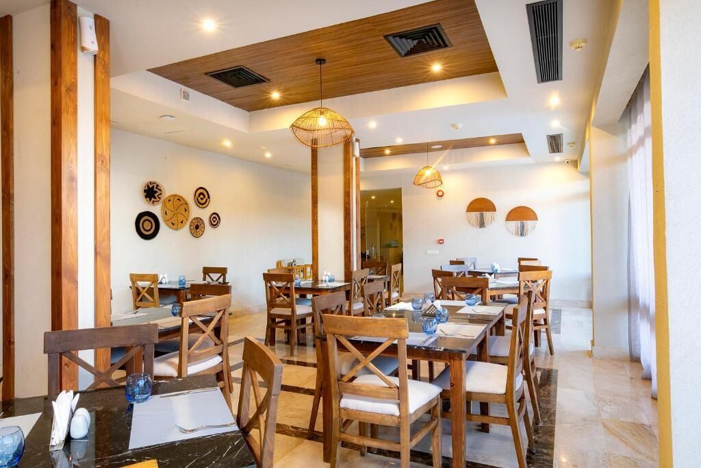 Un restaurante con mesas y sillas de madera, techo alto con vigas de madera y platos decorativos colgados en la pared.