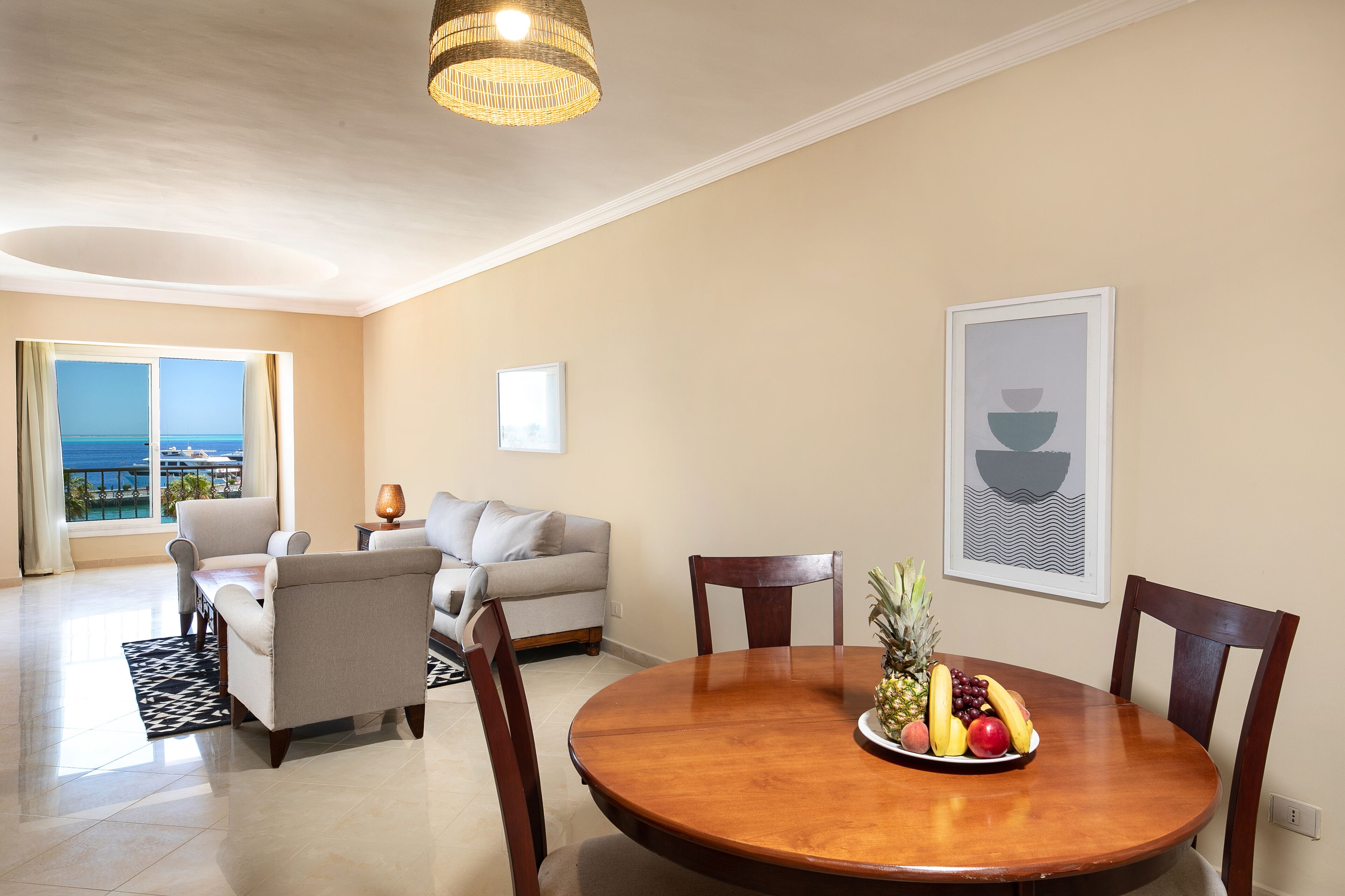 A dining area with a round wooden table, chairs, and a fruit bowl.