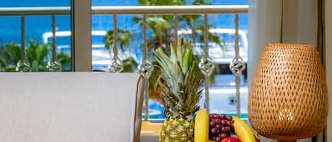 A balcony with a view of the ocean, a fruit plate, and a woven lamp.