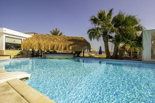Una piscina al aire libre, sombrillas, sillones reclinables de piscina
