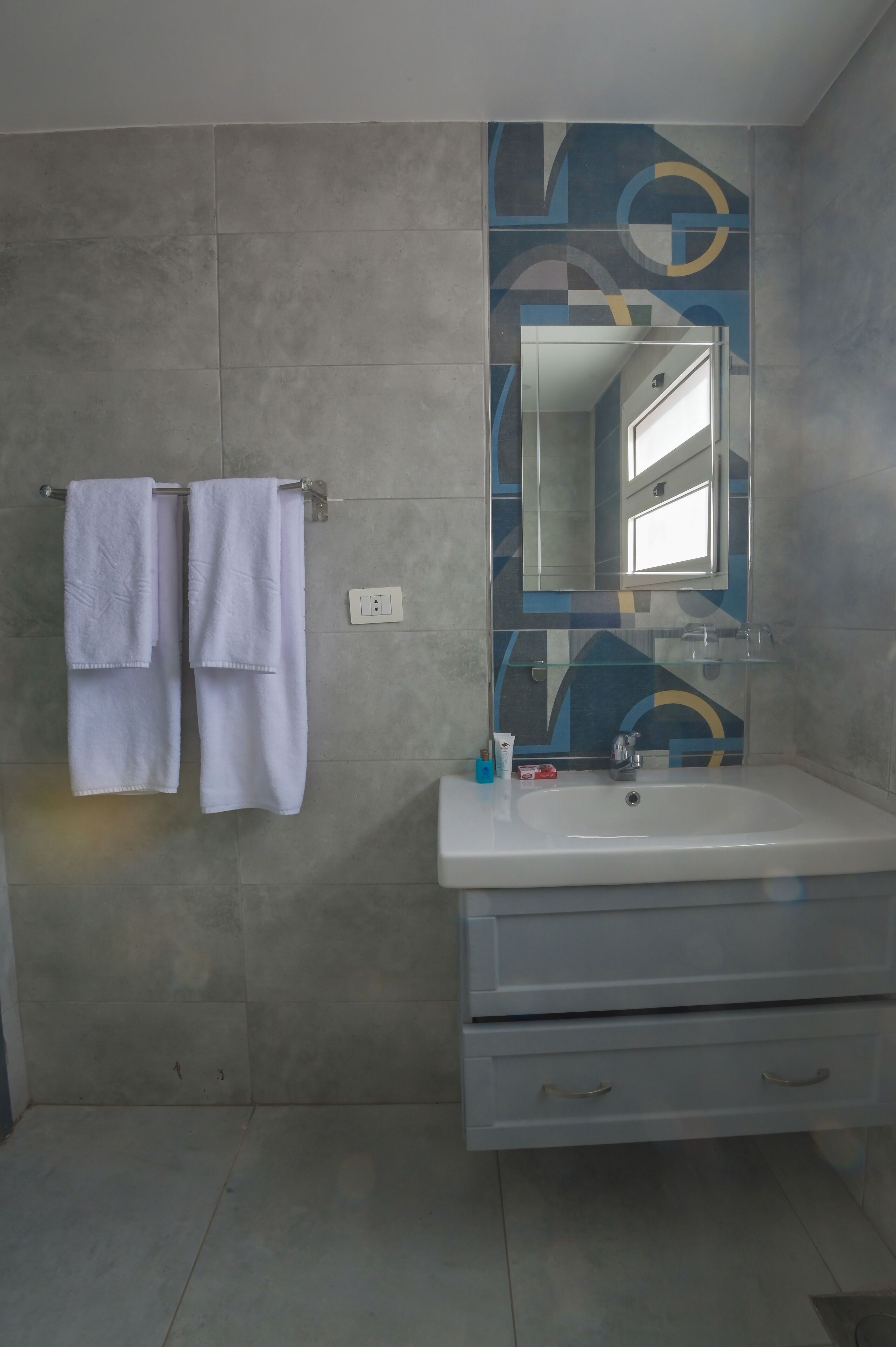 A bathroom with a white sink, a mirror, and two towels hanging on a rack.